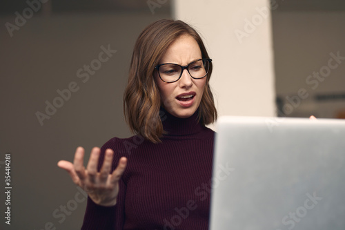 Attractive young woman in glasses looking frustrated at her laptop