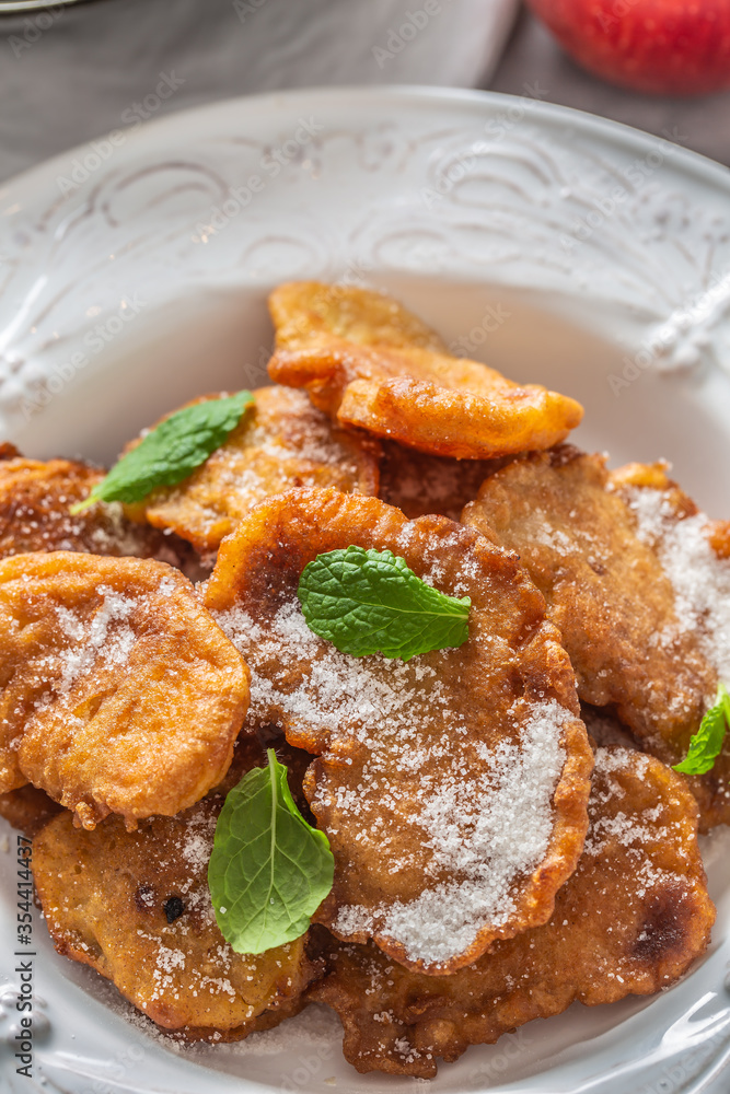 Finely fried apple pancakes sprinkled with vanilla sugar and cinnamon topped with mint leaves Finely fried apple pancakes sprinkled with vanilla sugar and cinnamon topped with mint leaves