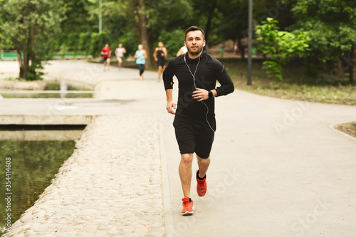 Portrait of jogging guy running in modern park
