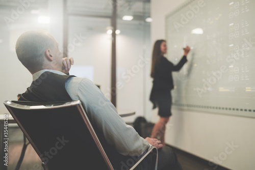 Fotografie View from behind of a boardroom with a businessman in an office armchair closely