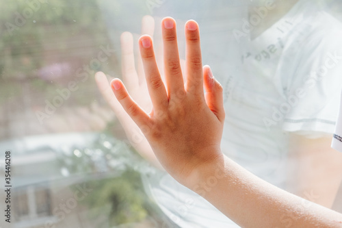 young baby boy looking through a window, child's hand on the window