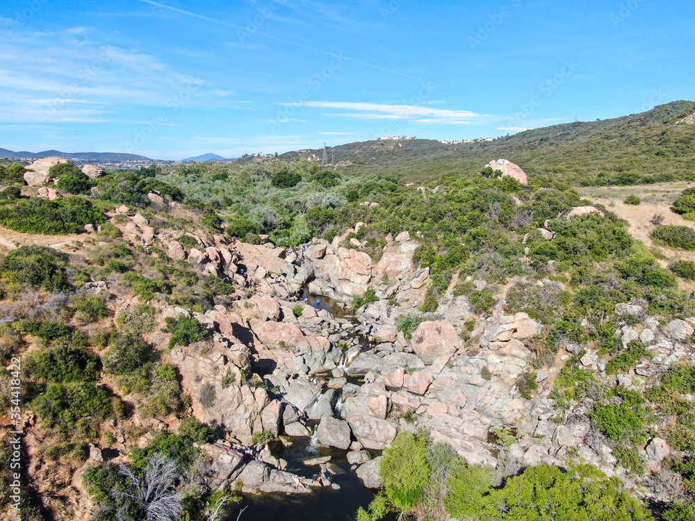 Aerial view of Los Penasquitos Canyon Preserve with the creek waterfall and people enjoying the water. Urban park with trails and river in San Diego, California. USA Aerial view of Los Penasquitos Canyon Preserve with the creek waterfall and people enjoying the water. Urban park with trails and river in San Diego, California. USA