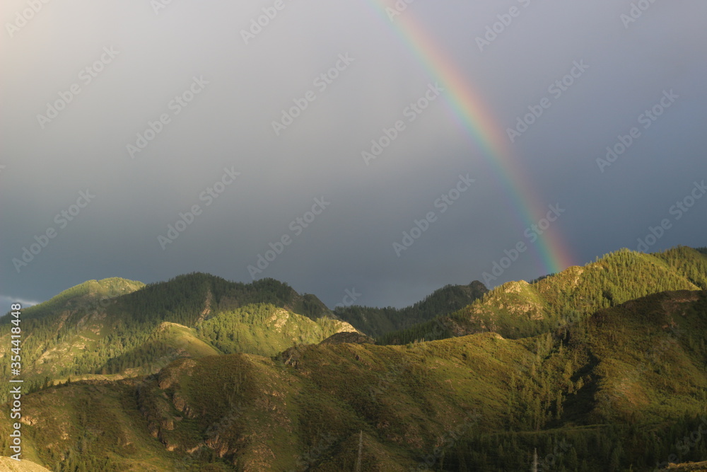 the Republic of Altai, Russia. A magnificent, juicy landscape with a rainbow on the background of a mountain ridge.