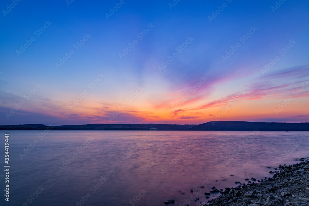 long exposure landscape evening twilight time after sunset lake calm water and main land horizon background peaceful scenic