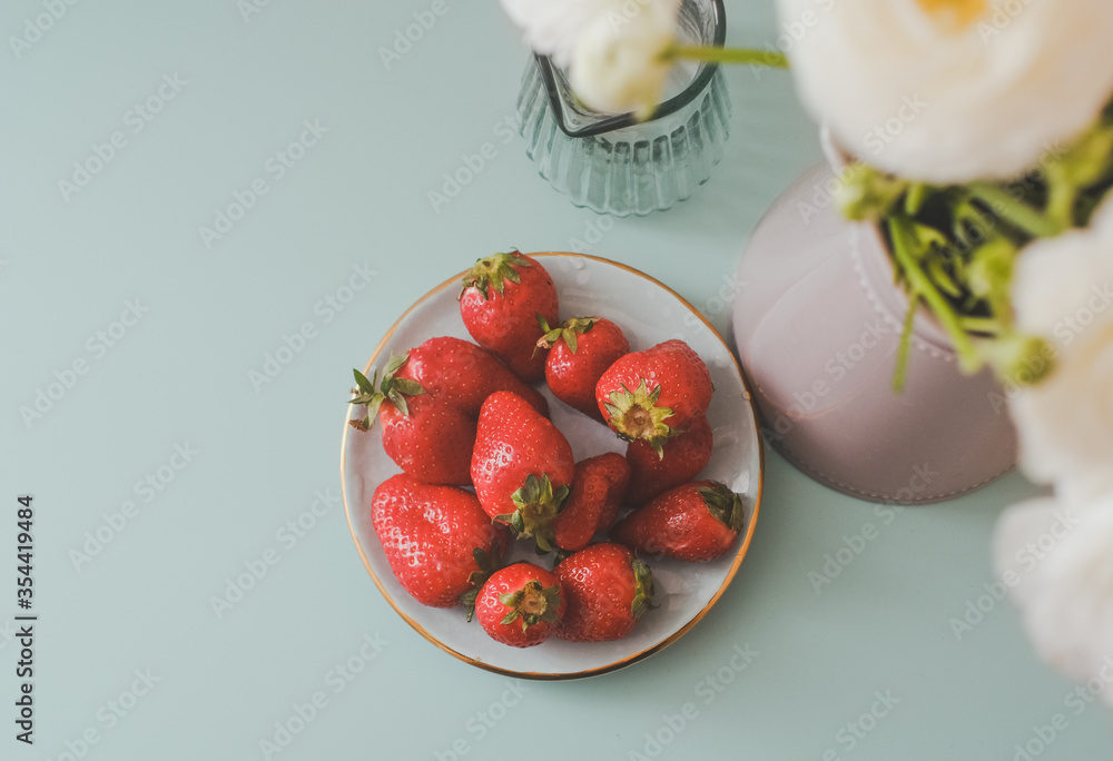 Fresh Strawberries and Flowers. Creative concept on Blue Background. Berries and White Ranunculus. Photo with film and grain effects Fresh Strawberries and Flowers. Creative concept on Blue Background. Berries and White Ranunculus. Photo with film and grain effects