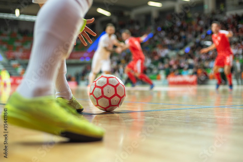 Futsal match - close up of ball in the corner and player's hand and legs. photo