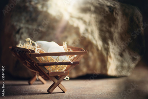 Christian Christmas concept. Birth of Jesus Christ. Wooden manger in cave background. Banner, copy space. Nativity scene symbol. Jesus is reason for season. Salvation, Messiah, Emmanuel, God with us.