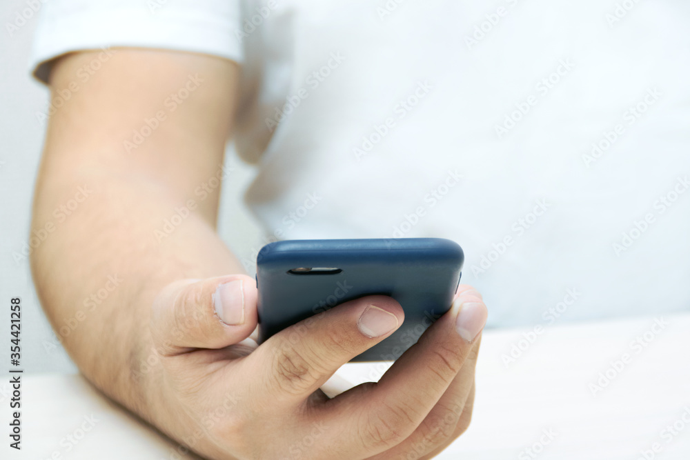 A person is holding a phone and tapping the screen on a white background with copy space. Concept of lifestyle business and Internet technologies in the office