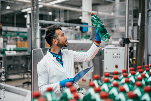 Male worker in bottling factory checking water ottles before shipment. Inspection quality control. photo