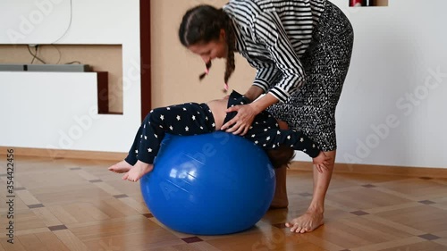 Mom does body exercises at home with her baby. Using a fitness ball