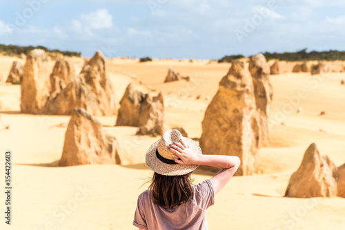 Woman tourist wearing hat, looking at scenic Pinnacles Desert in Nambung National Park in Western Australia. Concept of tourism, vacation travel and wanderlust photo