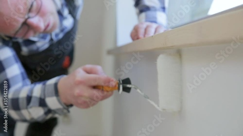 Home improvement concept, handyman painting a wall with a white paint near roof window in attic
