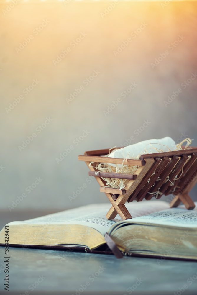 Obraz premium Birth of Jesus Christ. Wooden manger on Holy bible. Christian Christmas concept. Banner, copy space. Nativity scene symbol. Jesus is reason for season. Salvation, Messiah, Emmanuel, God with us, hope