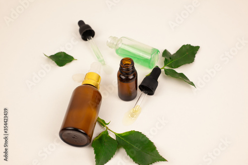 Fototapeta Naklejka Na Ścianę i Meble -  natural cosmetic skincare bottle container and organic green leaf on white background. Home made remedy and beauty product concept. Face serum, face oil, anti age care, face peeling. select focus