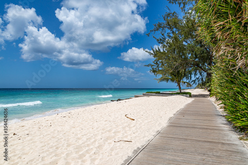 Looking along a wooden boardwalk running alongside a sandy Caribbean beach © lemanieh
