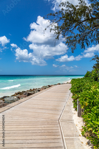 Fototapeta Naklejka Na Ścianę i Meble -  Looking along a wooden boardwalk running alongside a sandy Caribbean beach