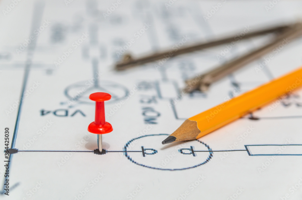 Red button and pencil on an electric diagram, working environment Red button and pencil on an electric diagram, working environment
