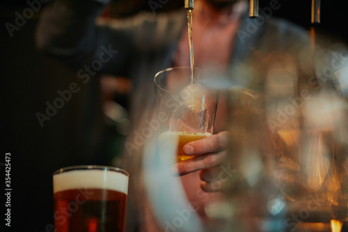 Closeup of man filling glass with beer.