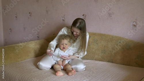 Beautiful attractive mother with a child sitting at home on the couch have fun considering pictures with animals.