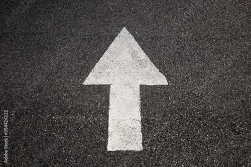 White arrow on a road of black asphalt pointing forward