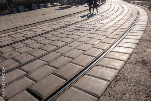 Tram ways in the city. 2 people are crossing the ways on sunny day. Background image.