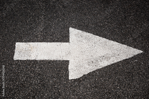 White arrow on black asphalt pointing to the right