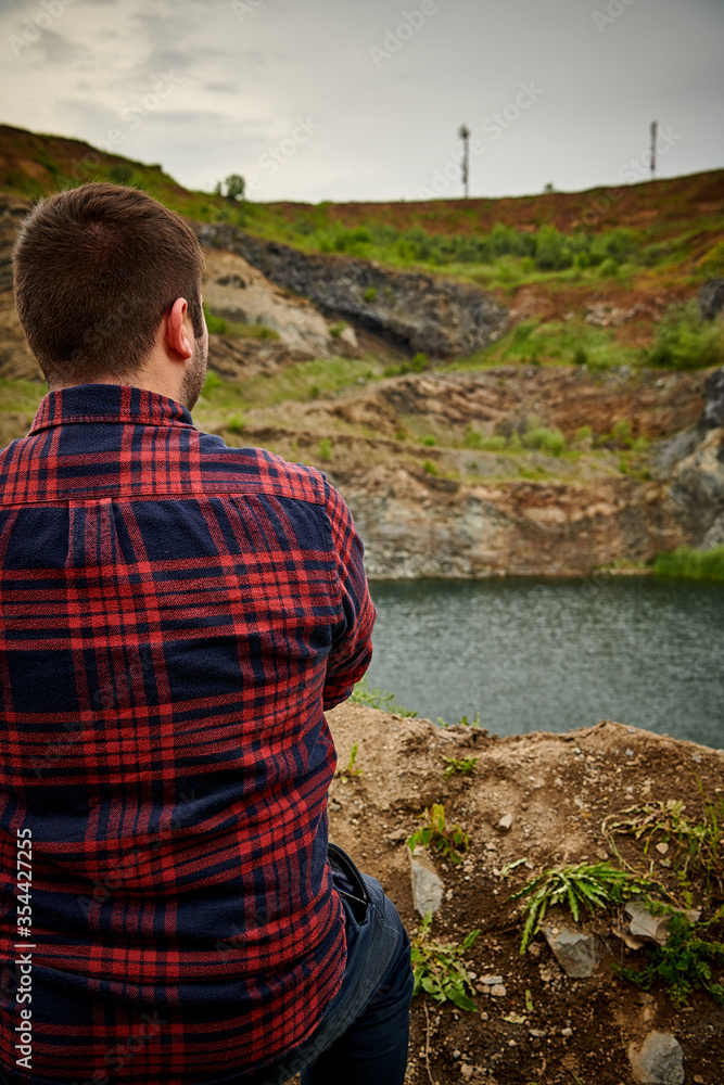 Naklejka premium Man looking at the lake on a cloudy day