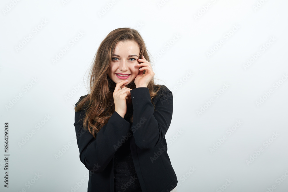 Young Attractive Woman Brunette In In A Black T-Shirt And Sweater On White Background, Cute Female Holding Hands Near Her Face, Gentle Person Young Attractive Woman Brunette In In A Black T-Shirt And Sweater On White Background, Cute Female Holding Hands Near Her Face, Gentle Person