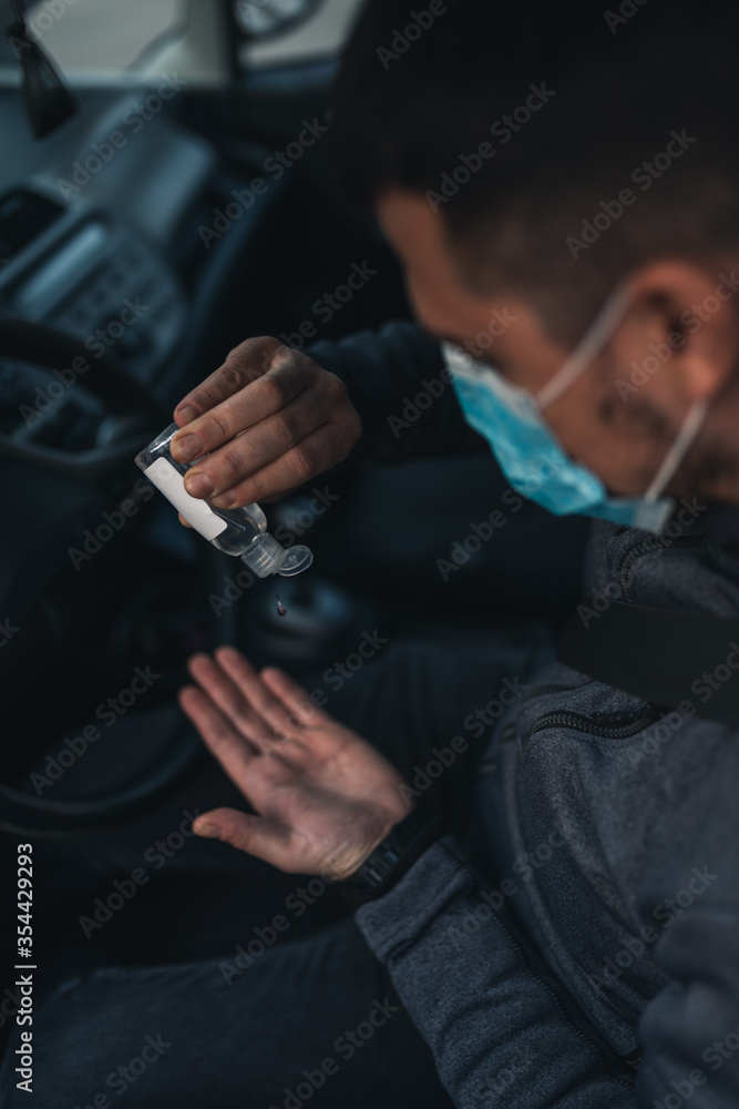 A man use an antiseptic gel into his hands while sitting in a car. A man in a medical mask to protect viruses. masked man in a car. coronavirus, disease, infection, quarantine, covid-19 A man use an antiseptic gel into his hands while sitting in a car. A man in a medical mask to protect viruses. masked man in a car. coronavirus, disease, infection, quarantine, covid-19