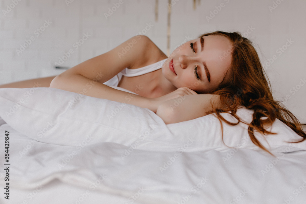 Pleased beautiful woman with trendy makeup sleeping with smile. Indoor photo of enchanting curly girl. Pleased beautiful woman with trendy makeup sleeping with smile. Indoor photo of enchanting curly girl.