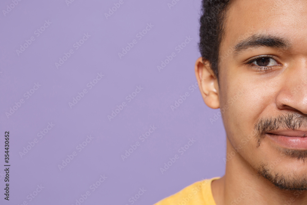 Obraz premium Cropped image up of young african american guy in casual yellow t-shirt posing isolated on violet background studio portrait. People emotions lifestyle concept. Mock up copy space. Looking camera.