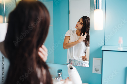 Portrait of young woman using hairdryer in bathroom
