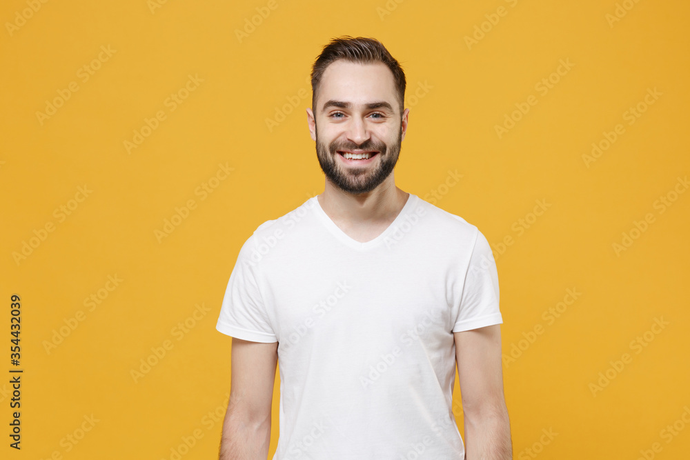 Smiling handsome young bearded man guy in white casual t-shirt posing isolated on yellow wall background studio portrait. People sincere emotions lifestyle concept. Mock up copy space. Looking camera. Smiling handsome young bearded man guy in white casual t-shirt posing isolated on yellow wall background studio portrait. People sincere emotions lifestyle concept. Mock up copy space. Looking camera.