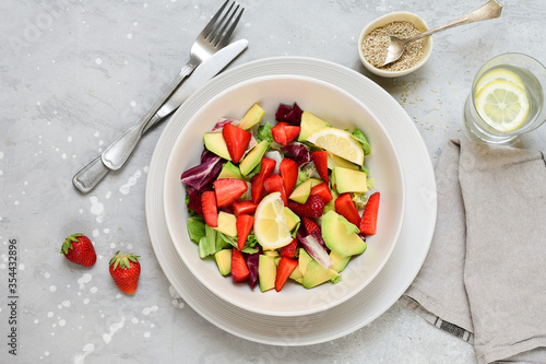 keto salad with avocado and strawberries on a white plate. kegogenic food recipe. healthy lunch or lunch