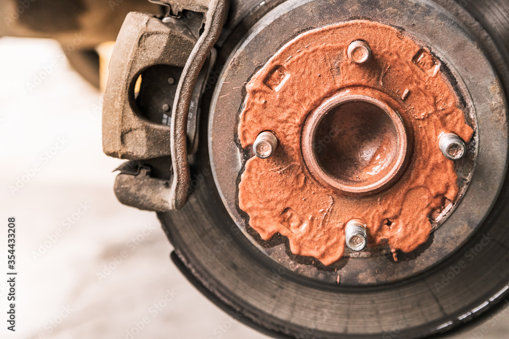 Old rusty worn brake discs are coated with copper grease in a passenger car. Car on a lift in a car service