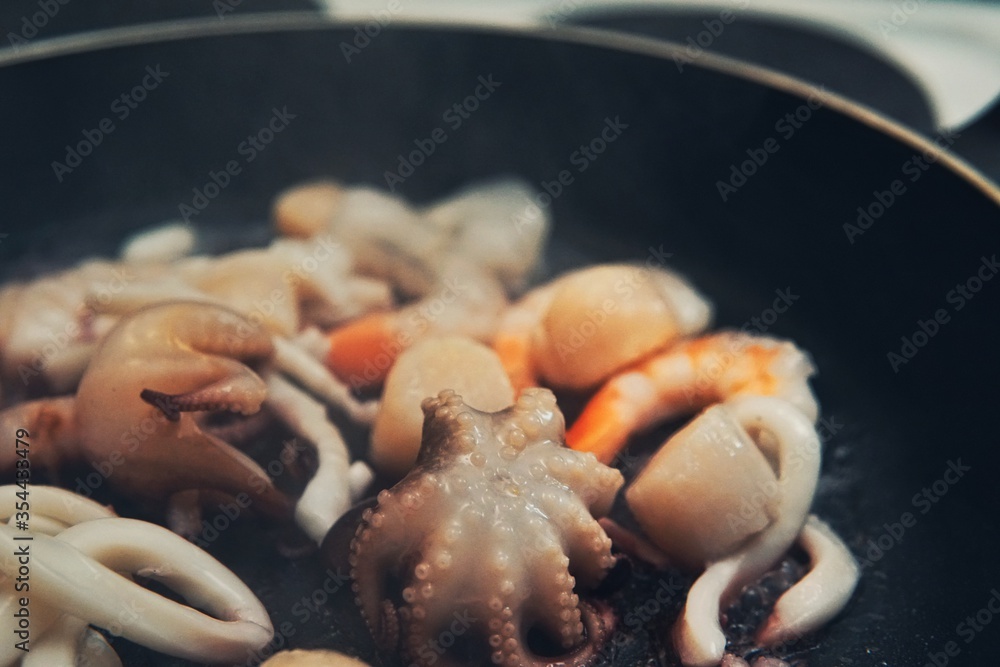 Seafood cocktail in black frying pan. Baby octopus, squid, shrimps, scallop. Seafood cocktail in black frying pan. Baby octopus, squid, shrimps, scallop.