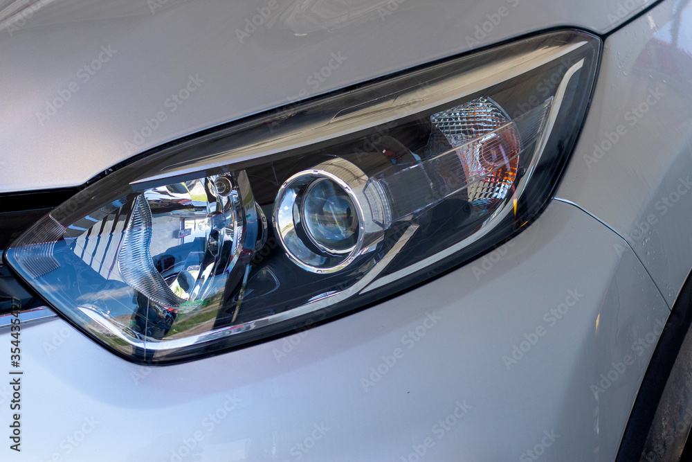The front light of the car. Modern halogen lighting. Front lighting of a silver car