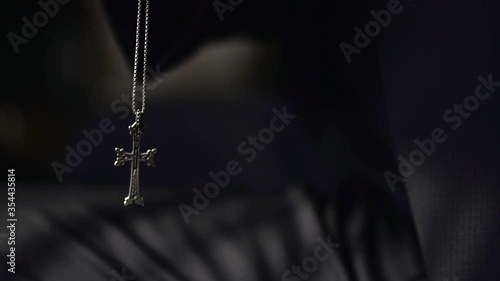 Groom clasped a cross in his hands. The silver cross in the hand. Catholic Cross. Silver pendant. Cristian Cross. Religion. 