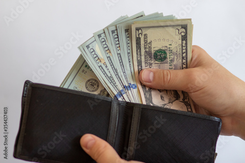 Pay with dollars. Get dollars out of your wallet. Dollar bills on a white background with a wallet
