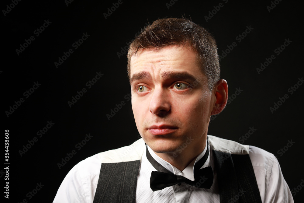 Portrait of a young and handsome man with emotion and funny face in black bow-tie isolated on black background.with copy space. Portrait of a young and handsome man with emotion and funny face in black bow-tie isolated on black background.with copy space.