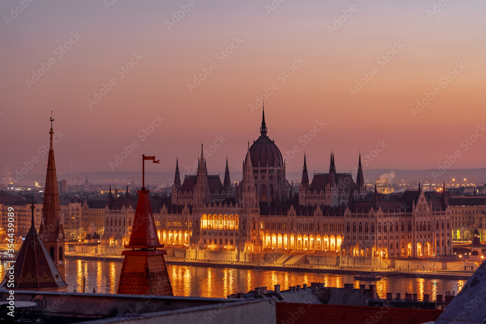 Hungary Parliament with lights on by Danube river in early morning before sunrise
