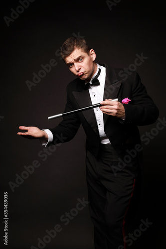 Funny magic man in tuxedo and bow tie with colorful handkerchief isolated on black background