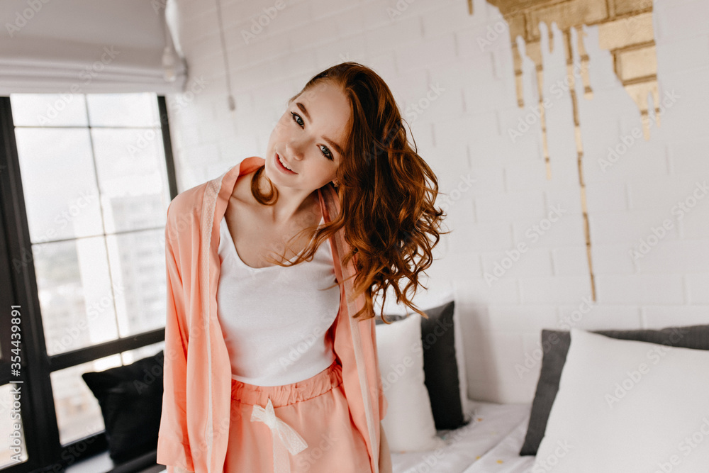 Interested lady with wavy hair expressing positive emotions. Jocund white girl in pajama smiling to camera. Interested lady with wavy hair expressing positive emotions. Jocund white girl in pajama smiling to camera.