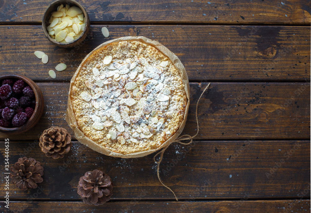 Grated rustic pie with ricotta, berries and almond flakes on dark wooden background Grated rustic pie with ricotta, berries and almond flakes on dark wooden background