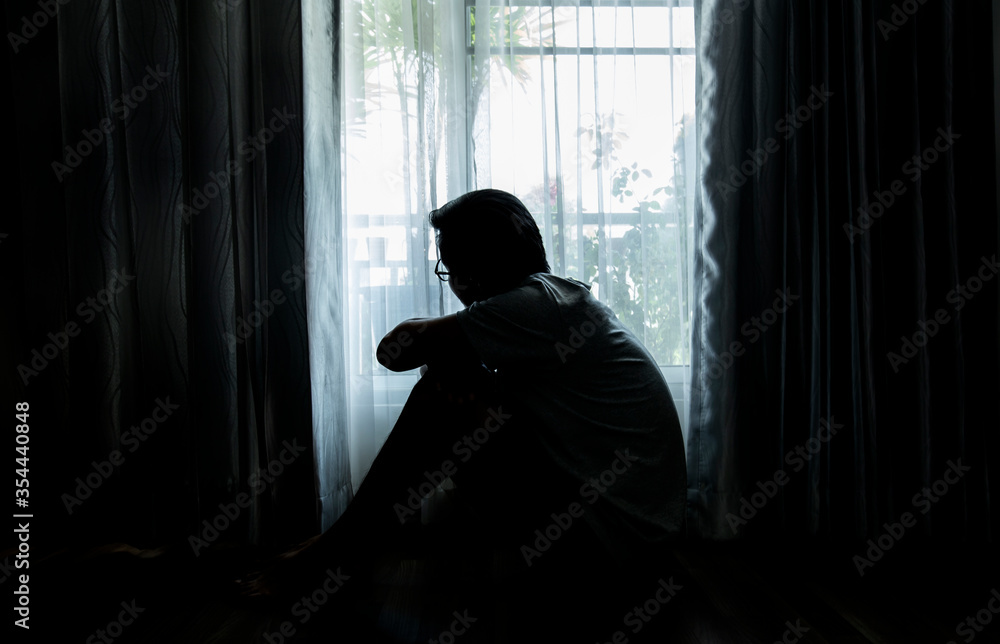 Sad young man sitting on the bed in the bedroom, People with depression concept.	
