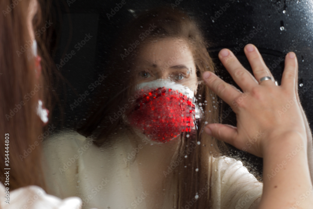 Fototapeta premium Woman in protective medical mask with rhinestones. Looking in the mirror.