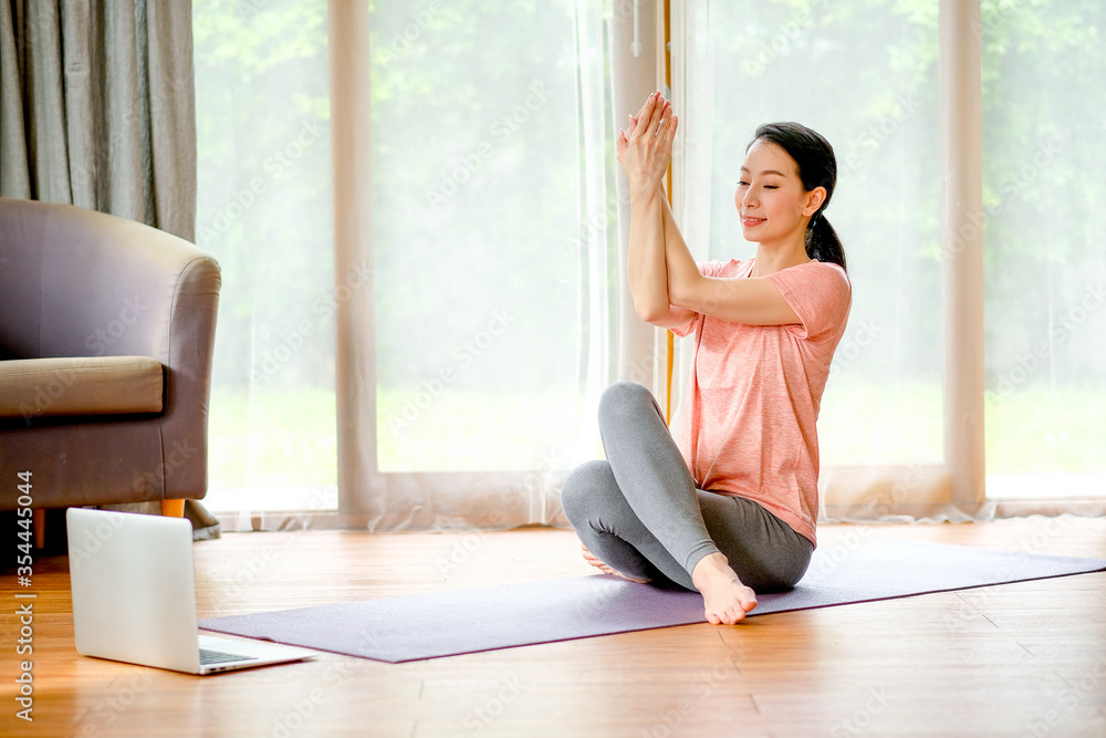 Beautiful women doing yoga with different posture and look example from laptop also she look happy and relax. Concept of workout at home for good health and prevent virus infection of pandemic. Beautiful women doing yoga with different posture and look example from laptop also she look happy and relax. Concept of workout at home for good health and prevent virus infection of pandemic.