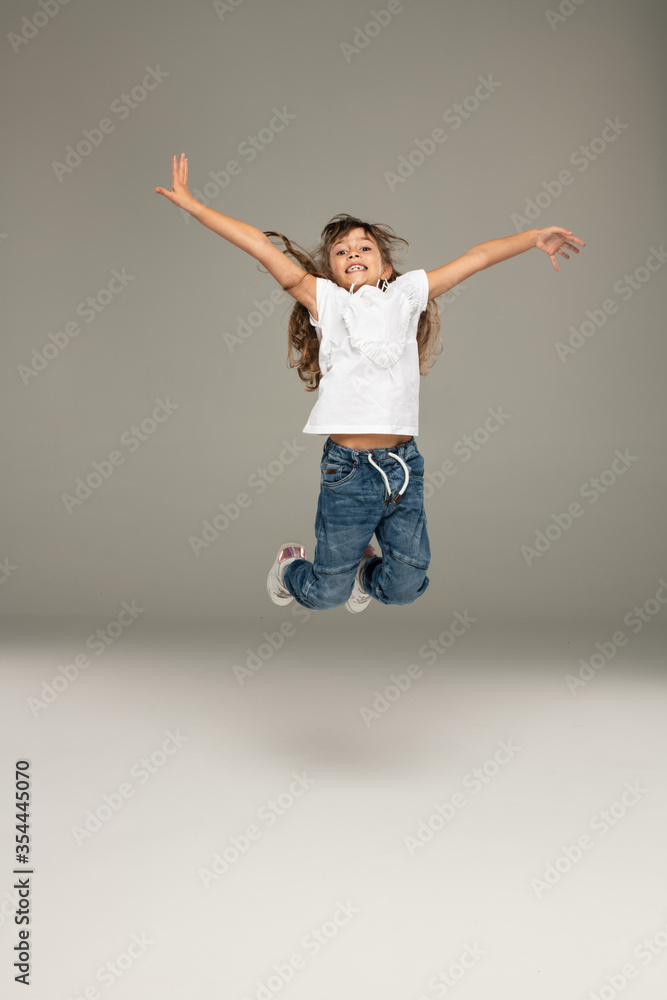 Happy jumping young girl wear blue jeans and white t-shirt