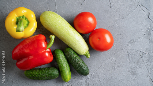 Summer set of vegetables. Ripe yellow and red bell peppers, cucumbers, tomatoes, zucchini on gray concrete