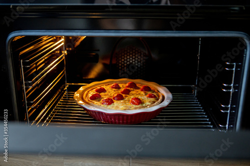 pie with chicken and tomatoes is on a baking sheet in the oven. quiche loren
